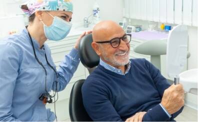 mature man looking at mirror and smiling - Church Street Dental Care Toronto